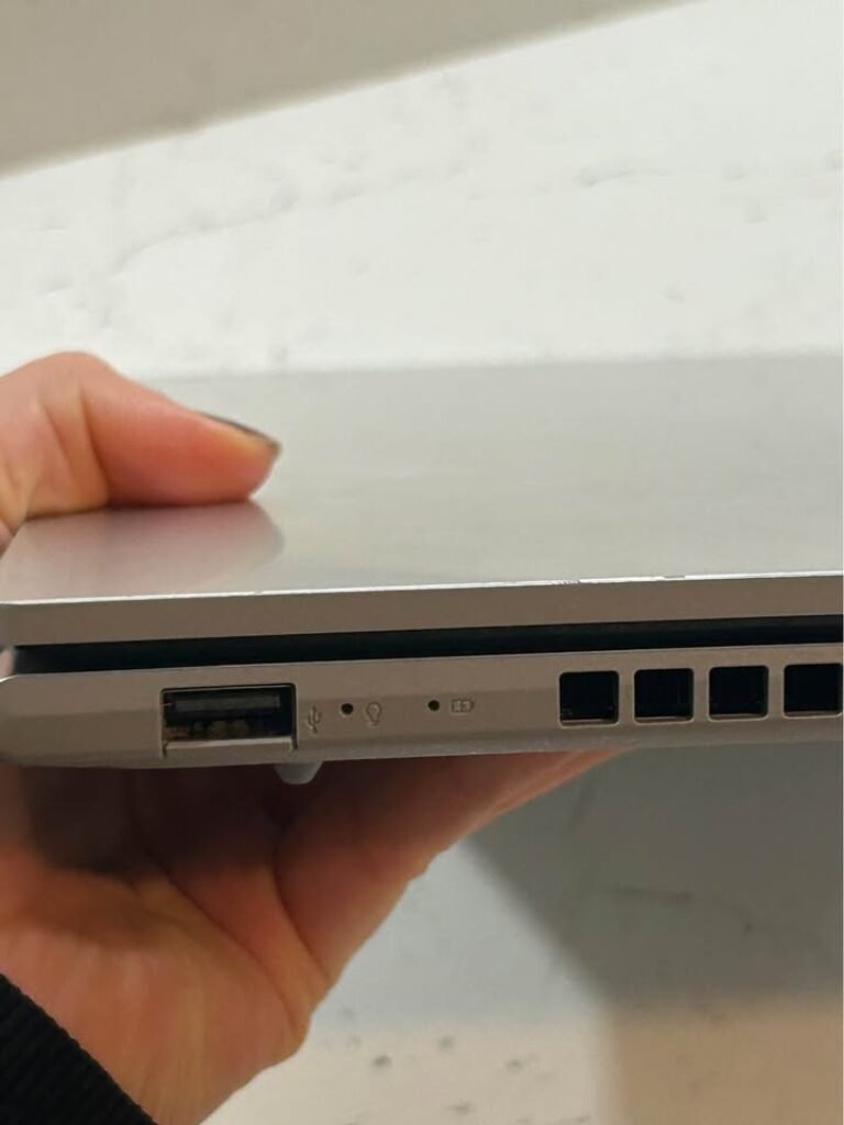 ASUS Vivobook Core i7 Laptop left side view showing USB-A port, LED power and charging indicator lights, and ventilation grilles on silver aluminum chassis