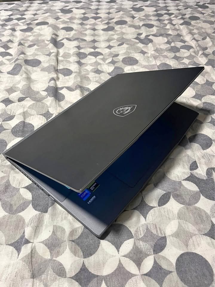 MSI Katana 15 gaming laptop powered by Intel Core i7 and RTX GPU, displayed in a three-quarter side profile showcasing the matte dark gray brushed polycarbonate chassis and dual-hinge construction.