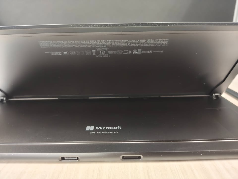 Microsoft Surface Pro 11 bottom edge featuring dual USB-C ports and open kickstand hinge, showcasing connectivity options on the dark anodized aluminum chassis